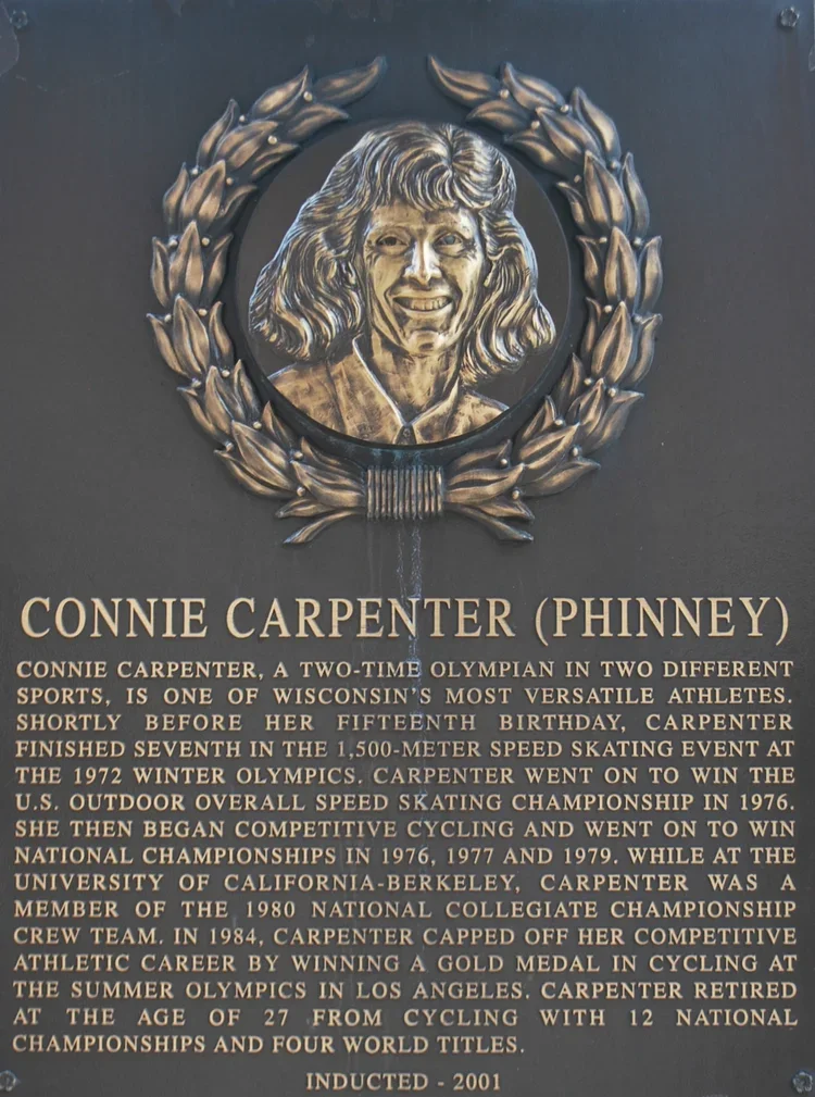 Plaque featuring a portrait of Connie Carpenter (Phinney), with a laurel wreath border, and information about her achievements in Olympic cycling.