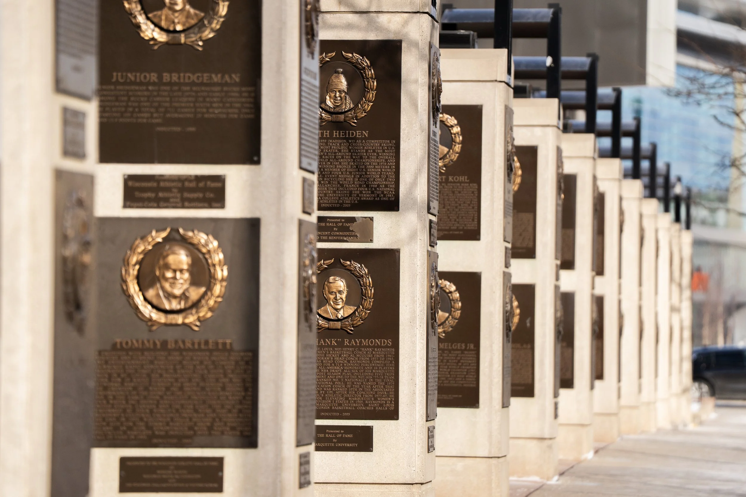 A row of plaques and bust sculptures honoring various individuals, with a focus on Tommy Bartlett in the foreground.