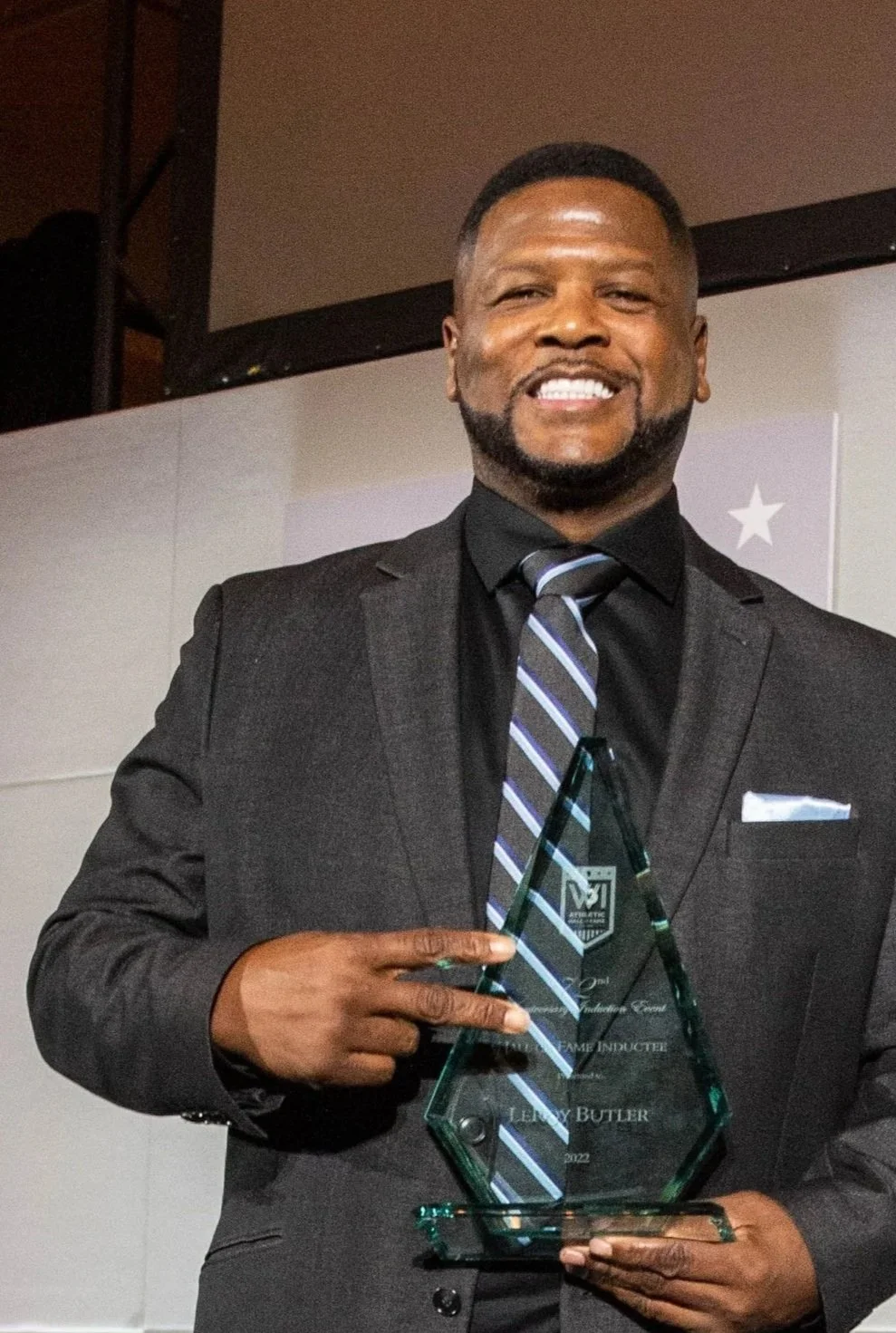 Man in black suit holding an award at an event.