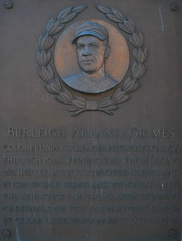A bronze plaque featuring a portrait of Lou Gehrig with a laurel wreath around his head. The inscription commemorates Burleigh Arland Grimes, a Major League Baseball pitcher from 1916 to 1934, who won 270 games and twice defeated Cleveland in the World Series.