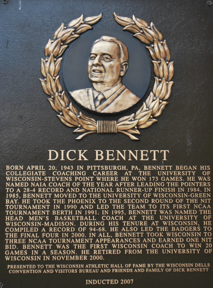 Plaque with a portrait of Dick Bennett, surrounded by a laurel wreath, and text detailing his career as a basketball coach.