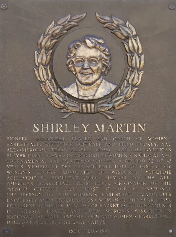 Plaque with a portrait of Shirley Martin surrounded by a laurel wreath. Text details her achievements in women's basketball, coaching, and sports advocacy.