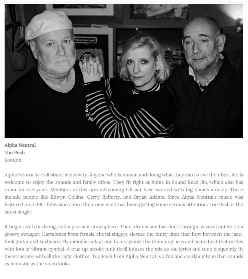 Black and white photo of three people standing close together indoors. The person on the left is a man wearing a hat, the person in the middle is a woman with shoulder-length hair, and the person on the right is a man with short hair. All are looking at the camera.