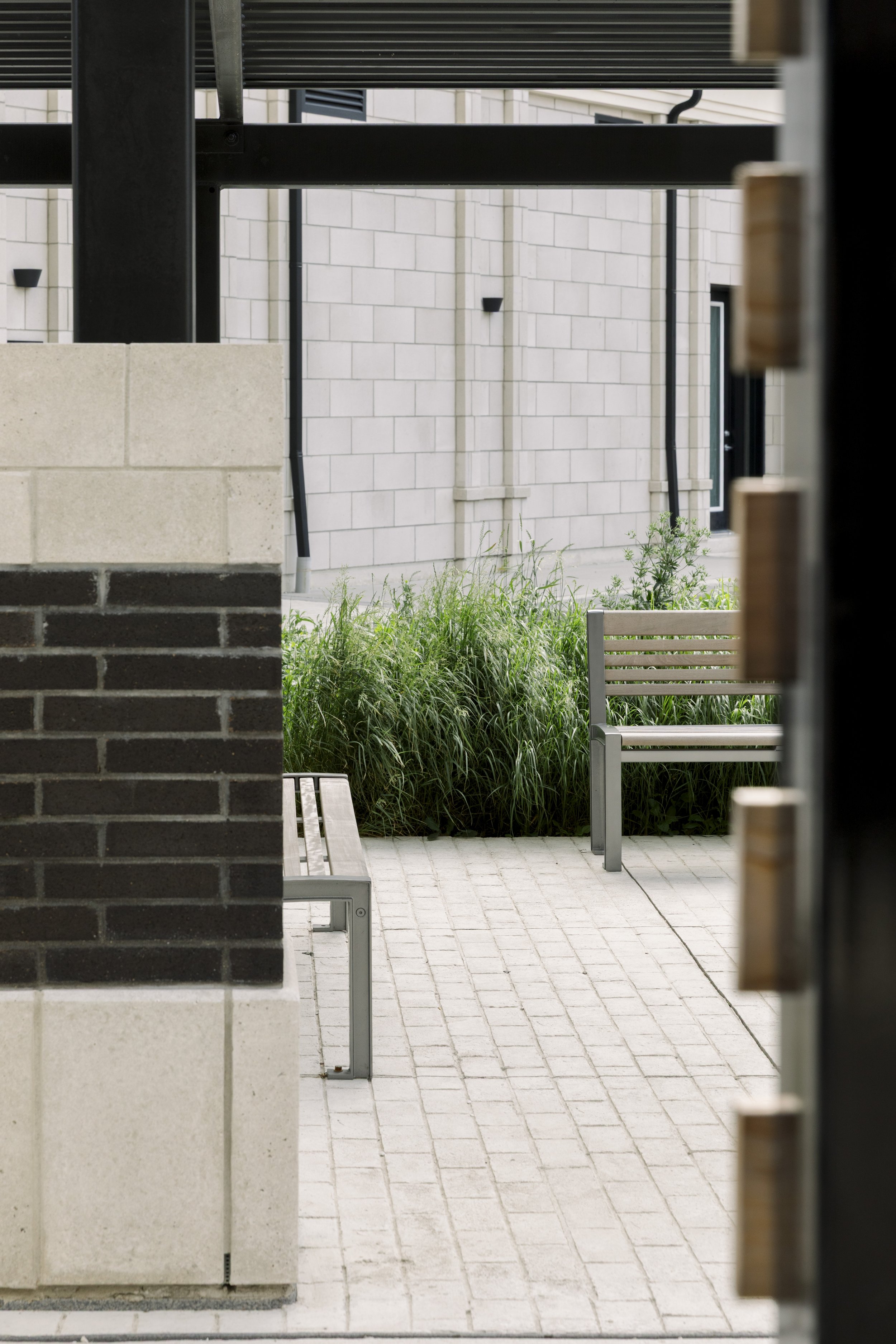 A view of benches and greenery in an urban courtyard area, framed by architectural elements.
