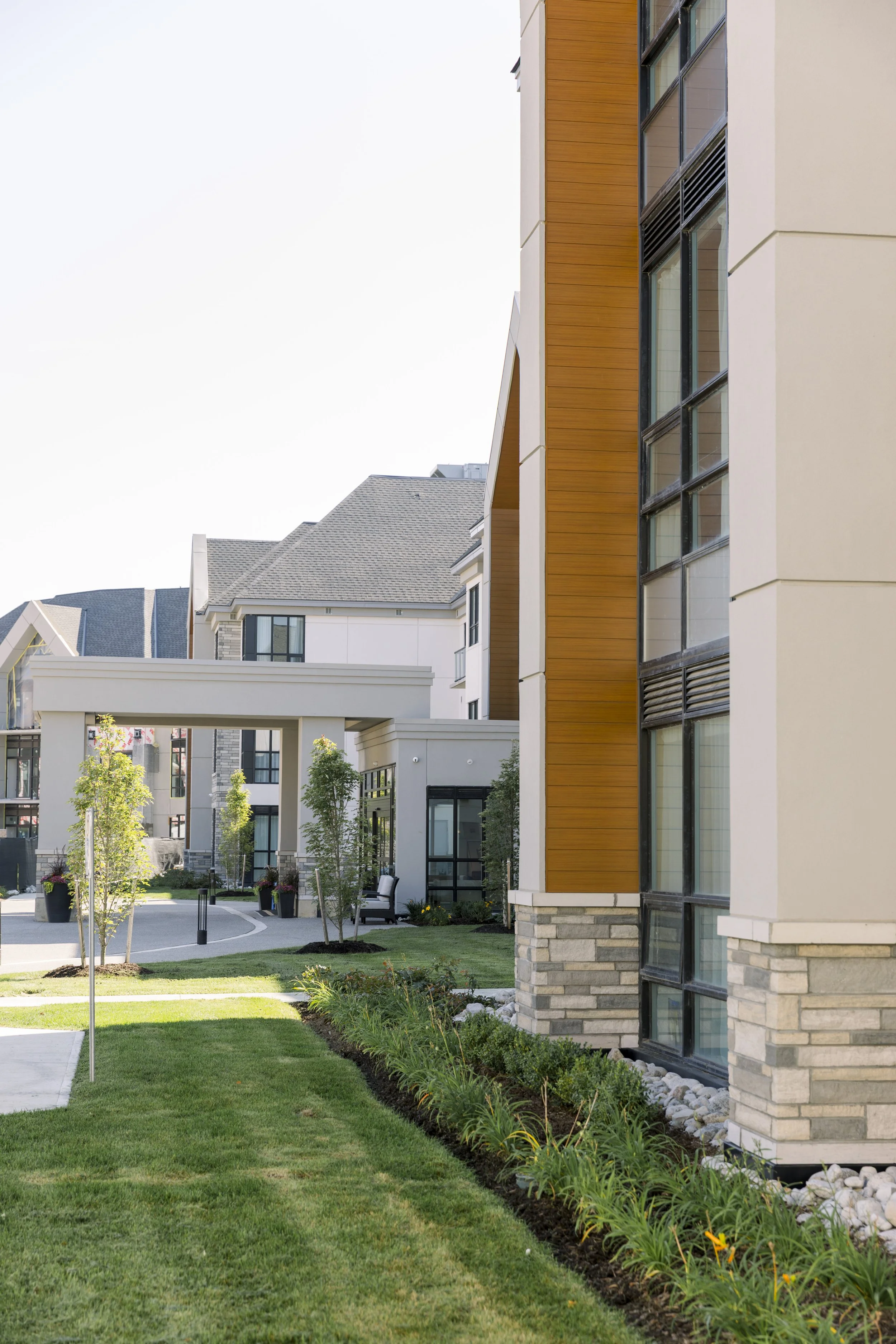 Modern apartment complex with landscaped lawn, trees, and outdoor seating areas.