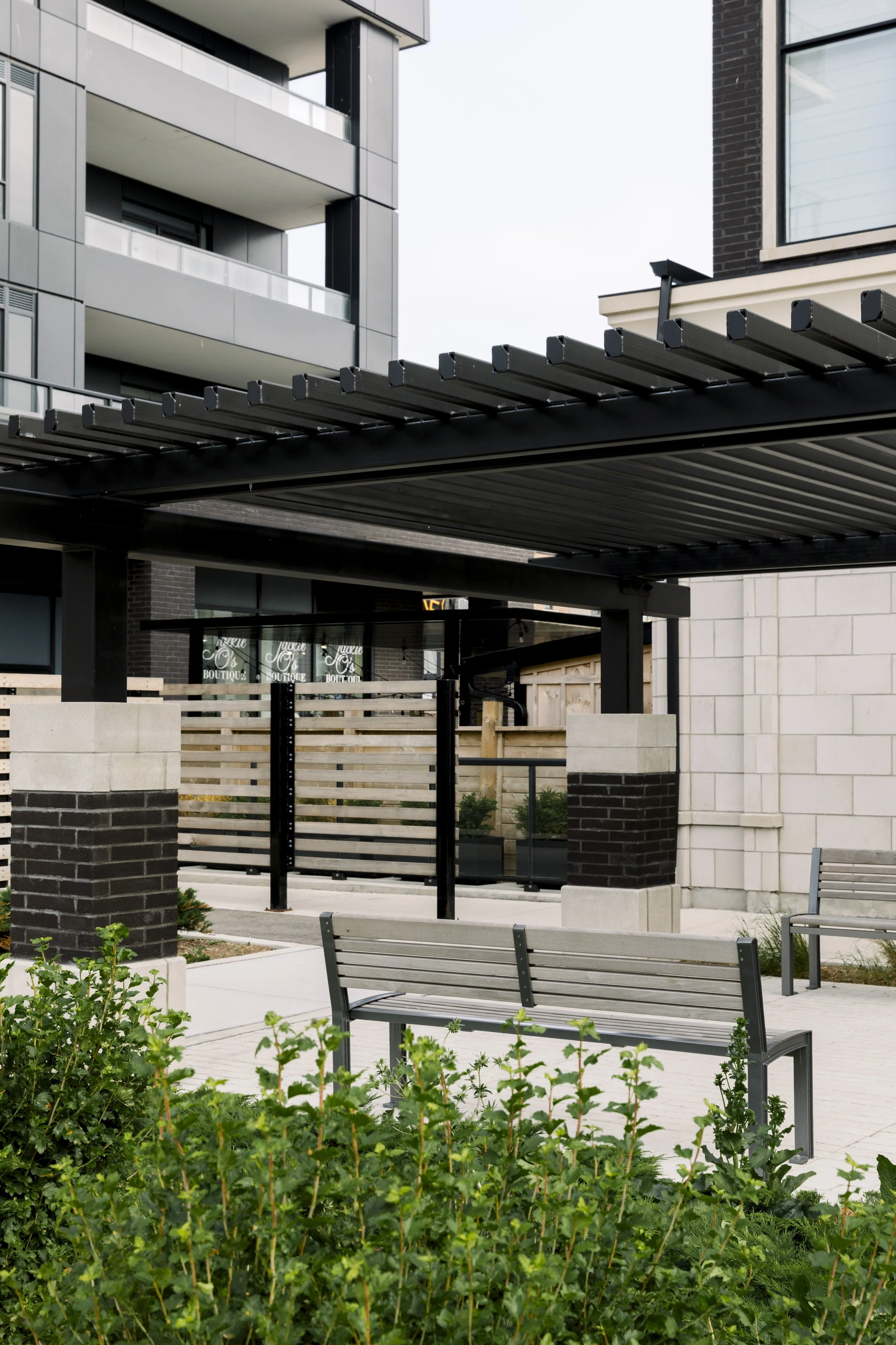 Modern apartment building with outdoor patio area, benches, and a pergola over the seating area.