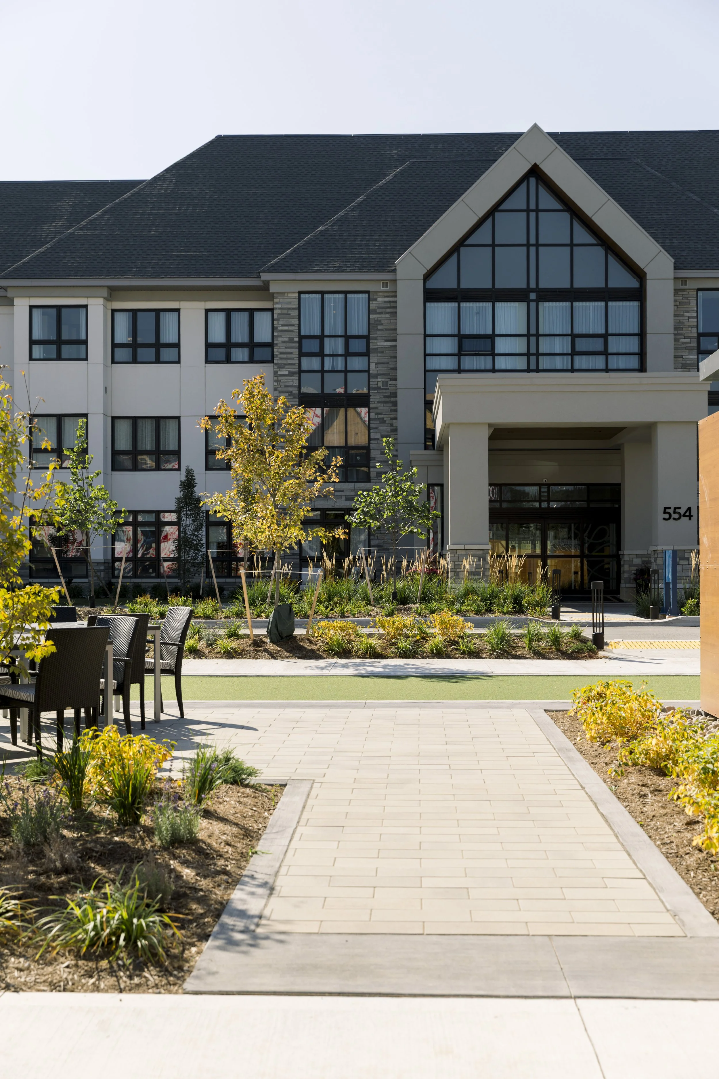Modern residential apartment building with landscaped garden and outdoor seating area.