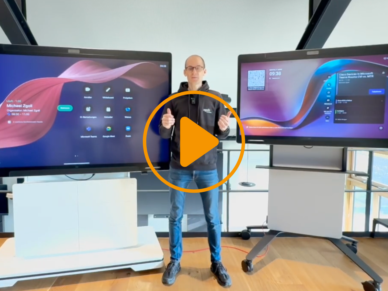 Michael Zgoll stellt vor, wie Cisco Video Device mit Microsoft Teams zu benutzen sind. Er steht vor zwei Medienstelen mit Displays.