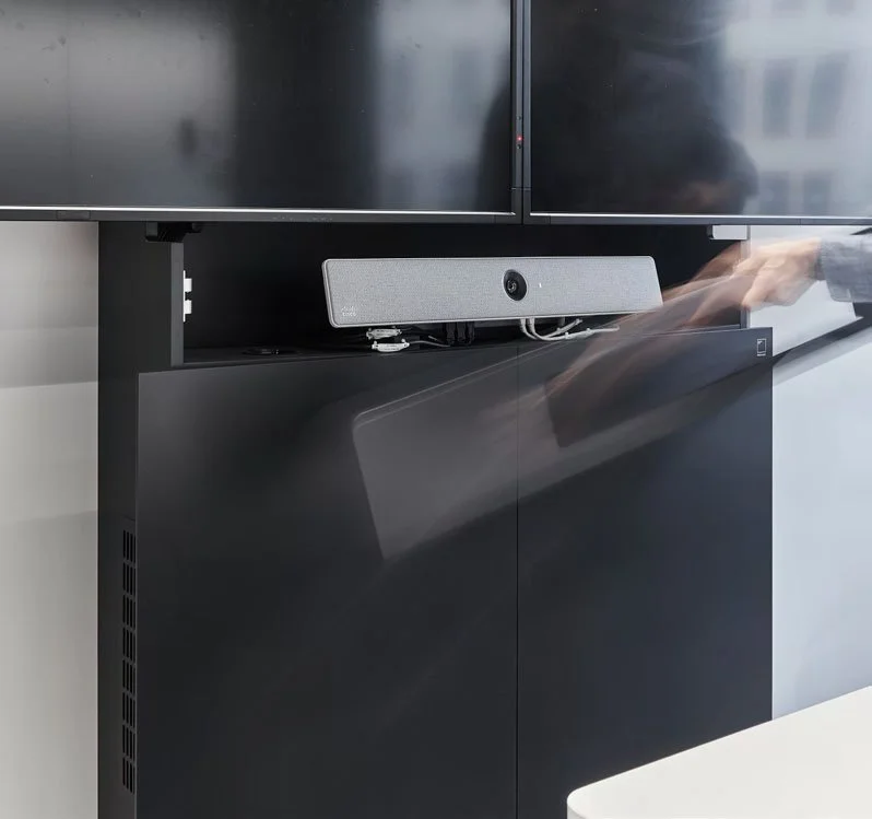 Ein schwarzer Fernseher auf einer schwarzen Möbelkonstruktion mit einem weißen Lautsprecher darunter.