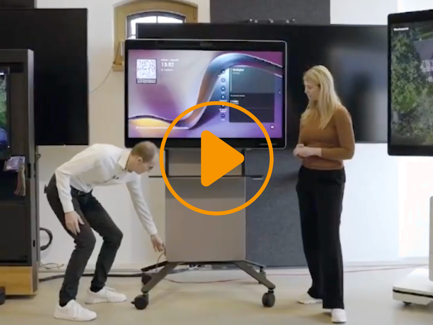 Ein Mann und eine blonde Frau stehen vor einer Medienstele von Wilkhahn.