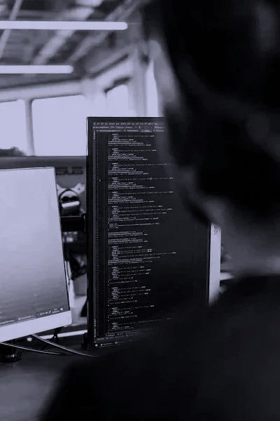 A person working on a computer with code displayed on the screen in an office setting.
