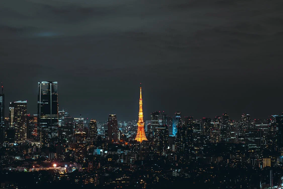 Nighttime finance capital city skyline with Tokyo Tower illuminated in orange.