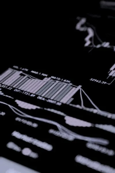 Close-up of a financial chart on a digital device screen with bar graphs and data points in a dark setting.