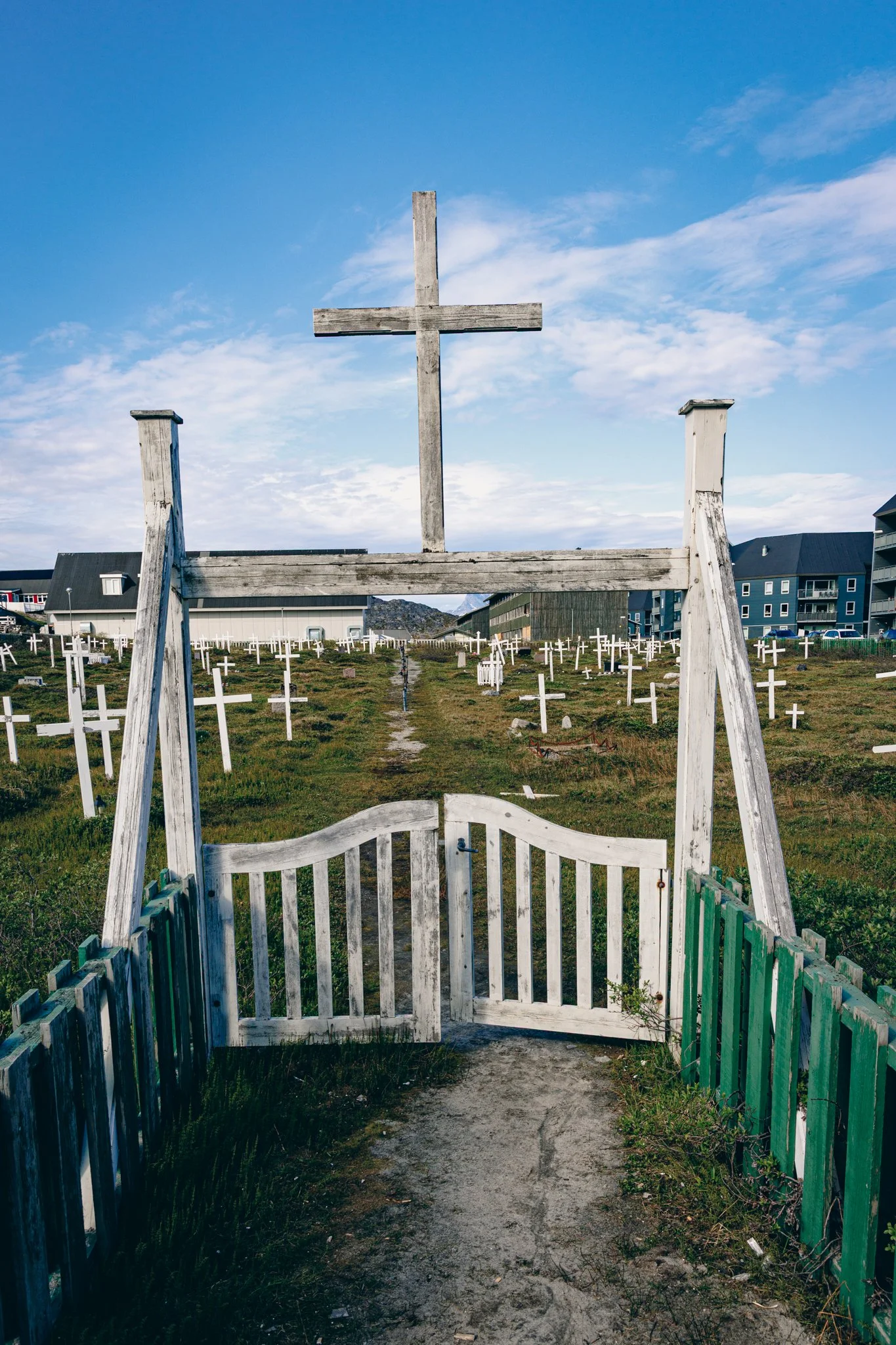 Stary cmentarz w Nuuk — rzędy prostych, białych krzyży rozrzuconych w surowym, arktycznym krajobrazie tworzą miejsce pełne ciszy i refleksji. Minimalistyczna forma nagrobków i naturalne otoczenie oddają charakter Grenlandii, gdzie pamięć o zmarłych w