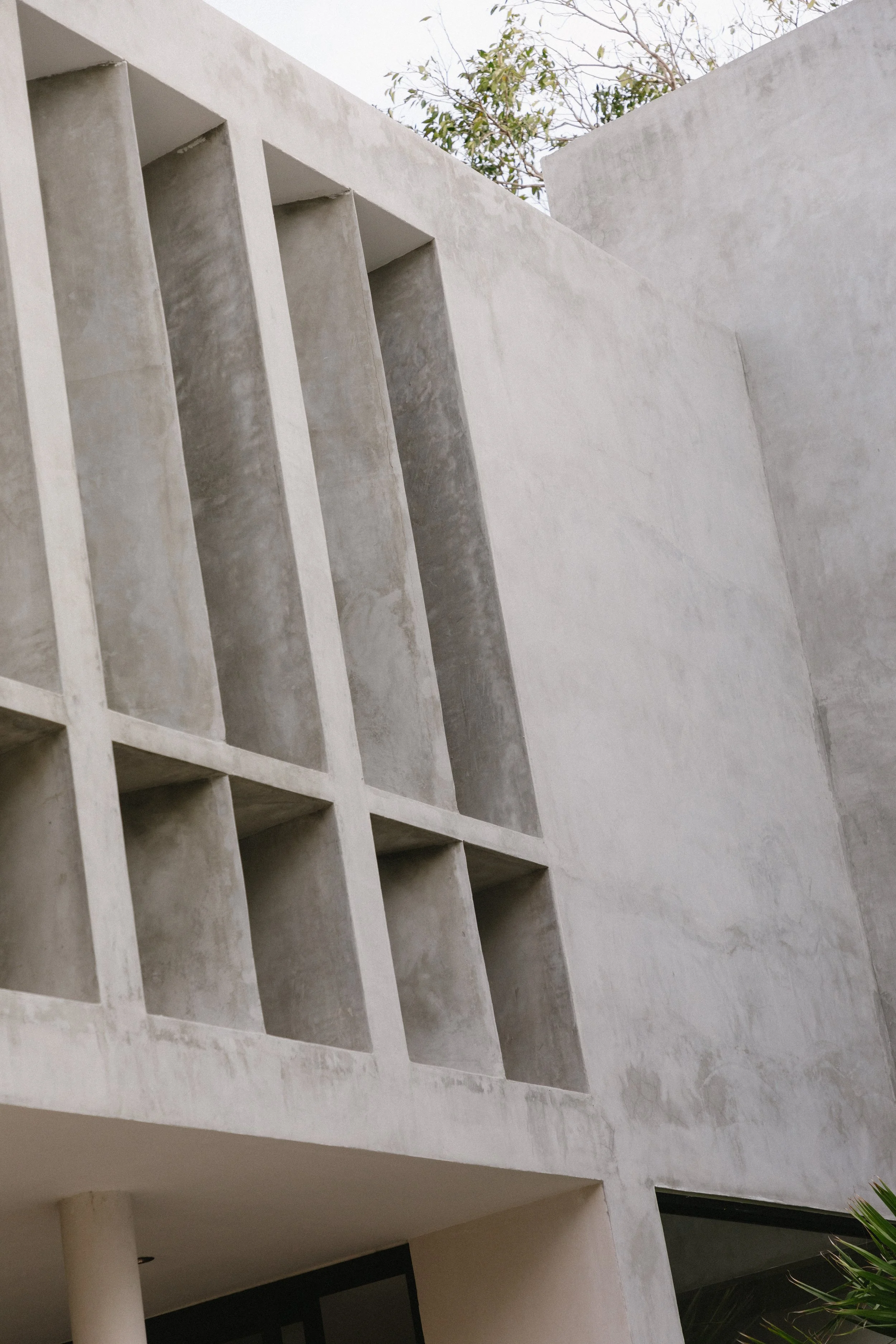 Modern building with tall, rectangular concrete windows and smooth white exterior walls.