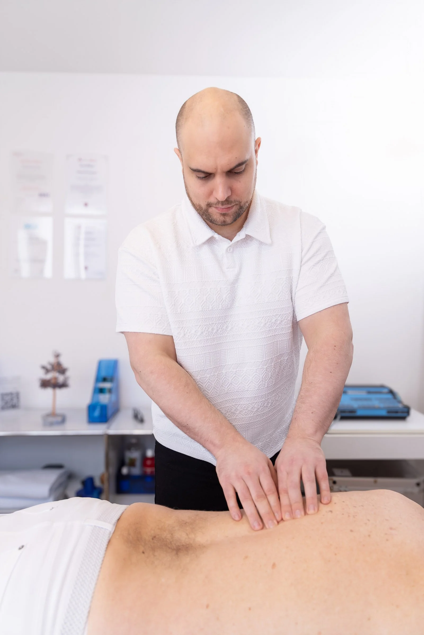 Mann führt eine Massage an einem Rücken durch in einem Behandlungsraum.