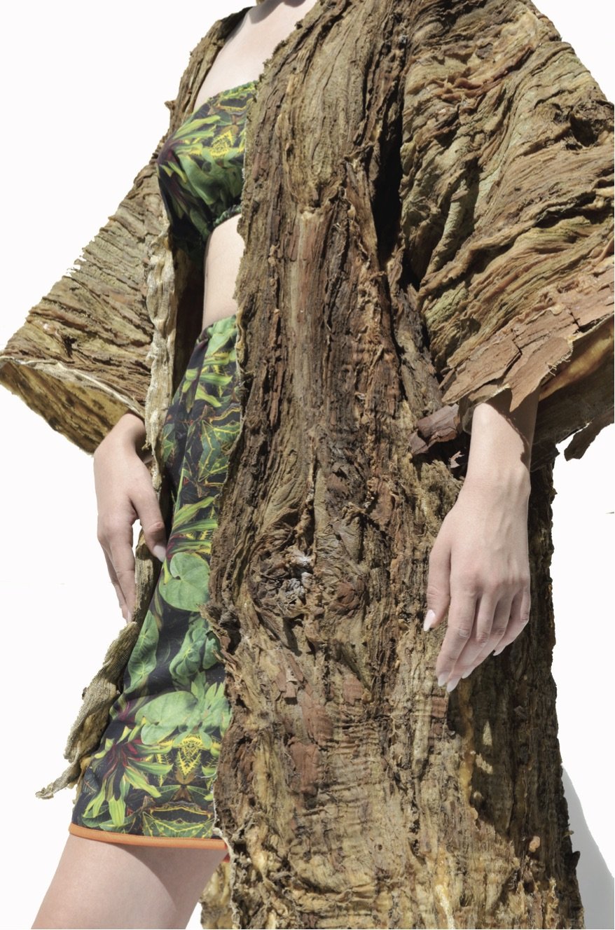 Une personne habillée avec un vêtement à motif de feuilles et un manteau en écorce d'arbre.