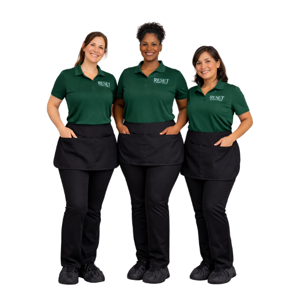 Three women standing together wearing green shirts with 'RESET' logo and black pants, smiling against a plain background.