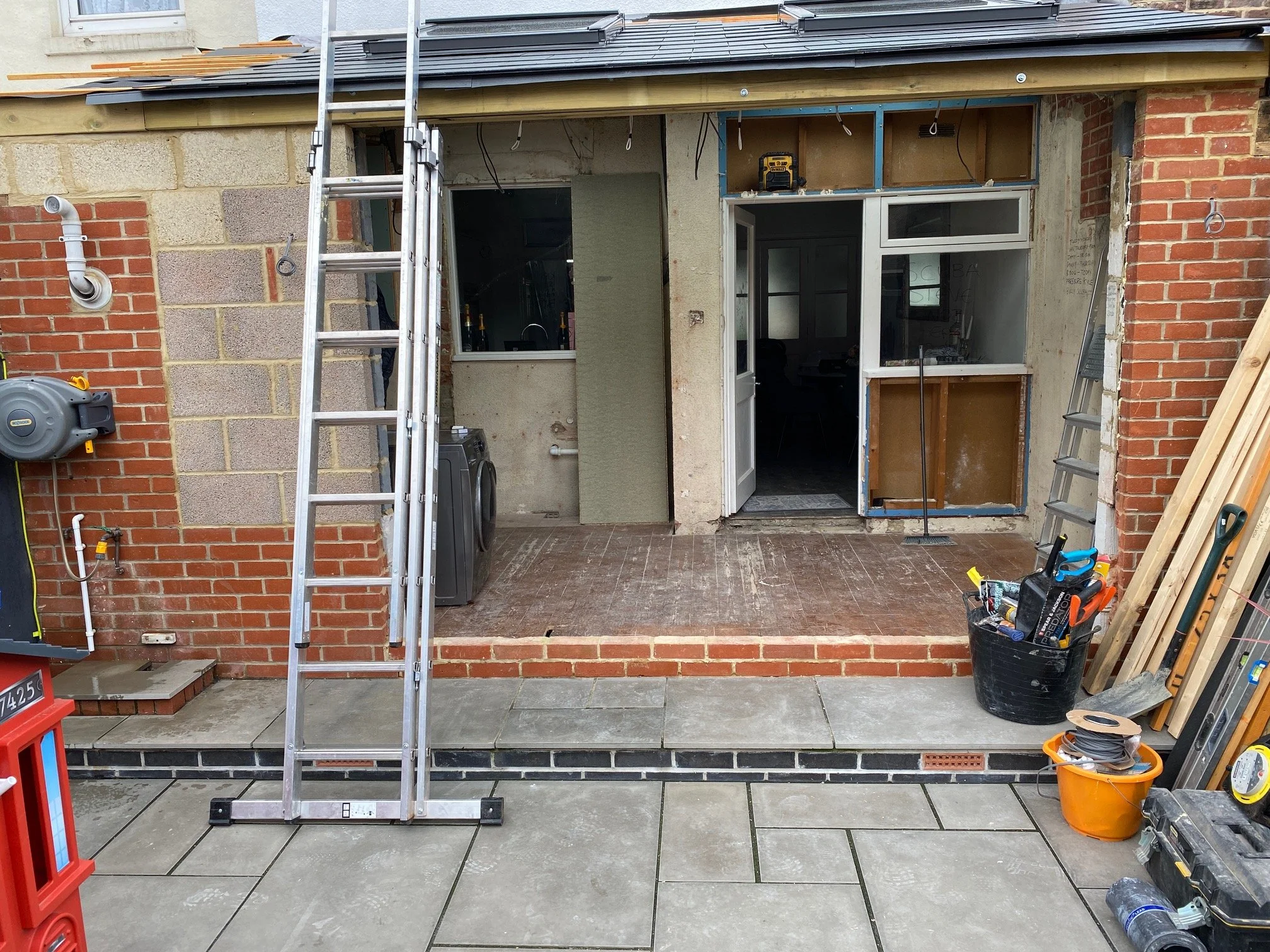 Undergoing home renovation with construction tools, ladders, and building materials on a partially completed porch or deck