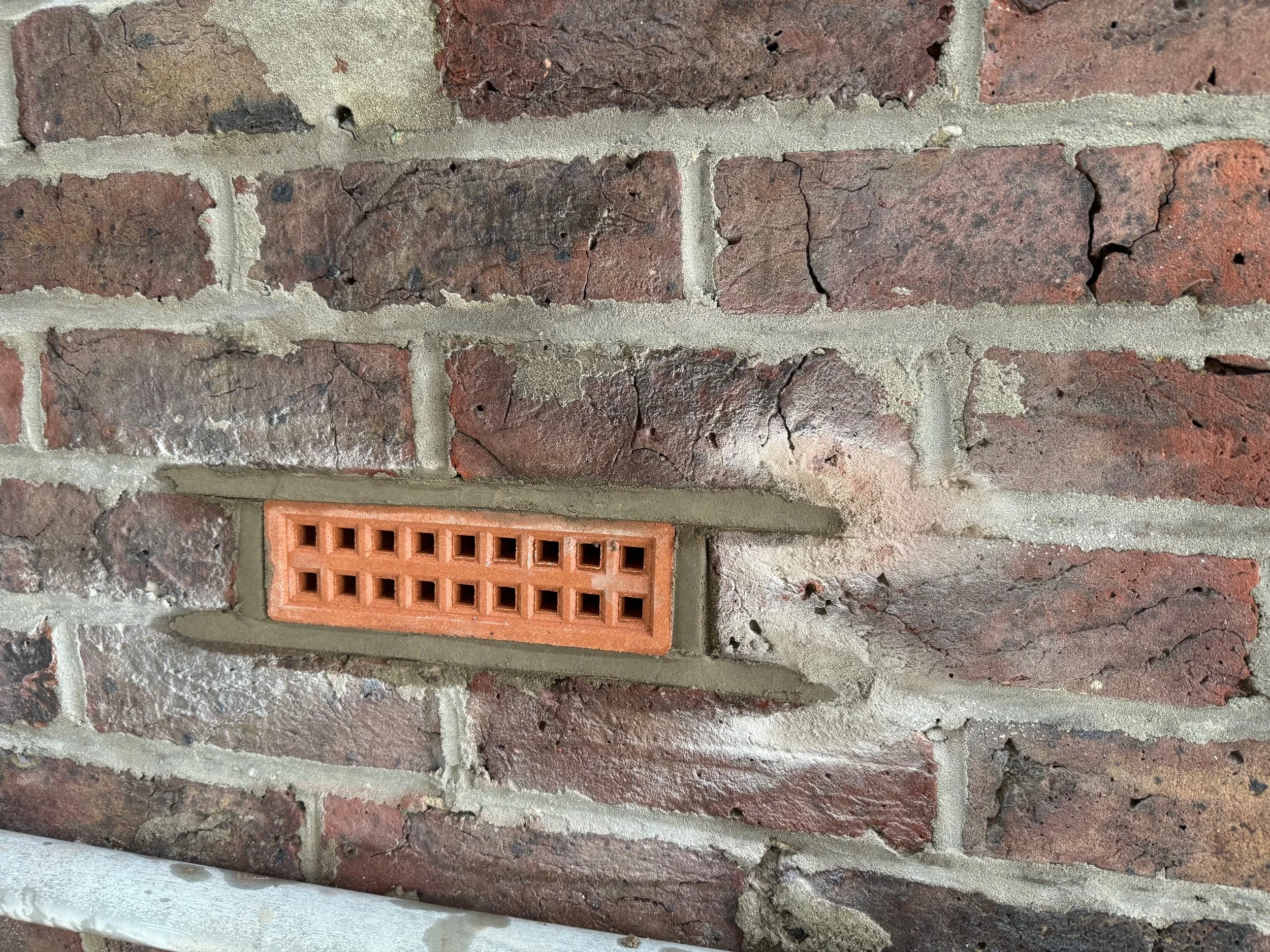 Close-up of a brick wall with a rectangular vent.