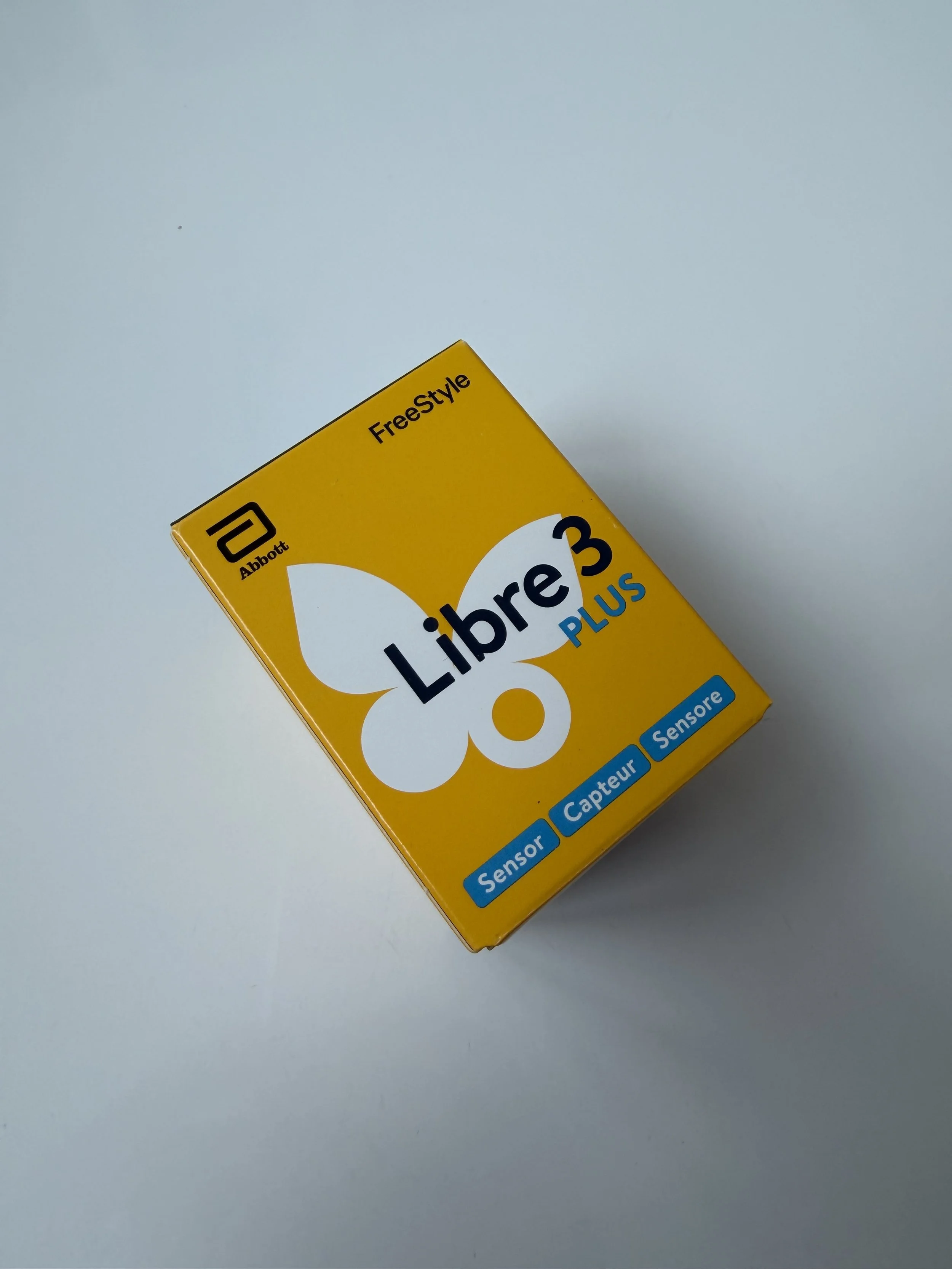 Yellow box labeled 'Libre 3 PLUS' with the Abbott logo, indicating it contains a sensor for diabetes management.