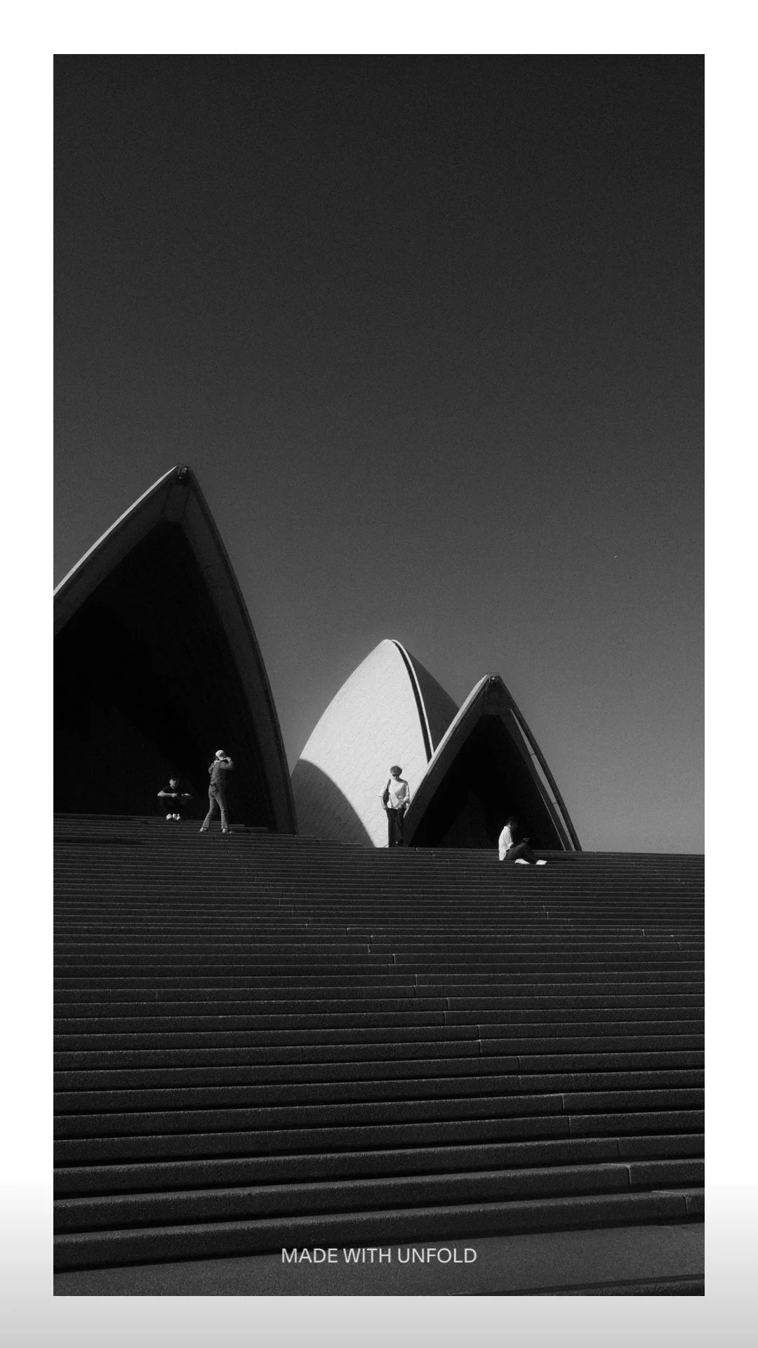 Black and white photo of the Sydney Opera House with a few people on the stairs in front of it.