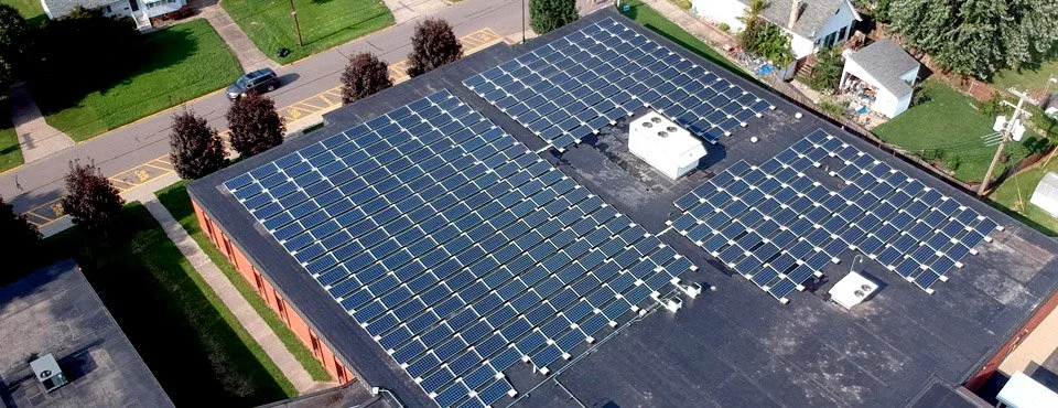 bird's eye view of a rooftop solar panel array on a flat school roof