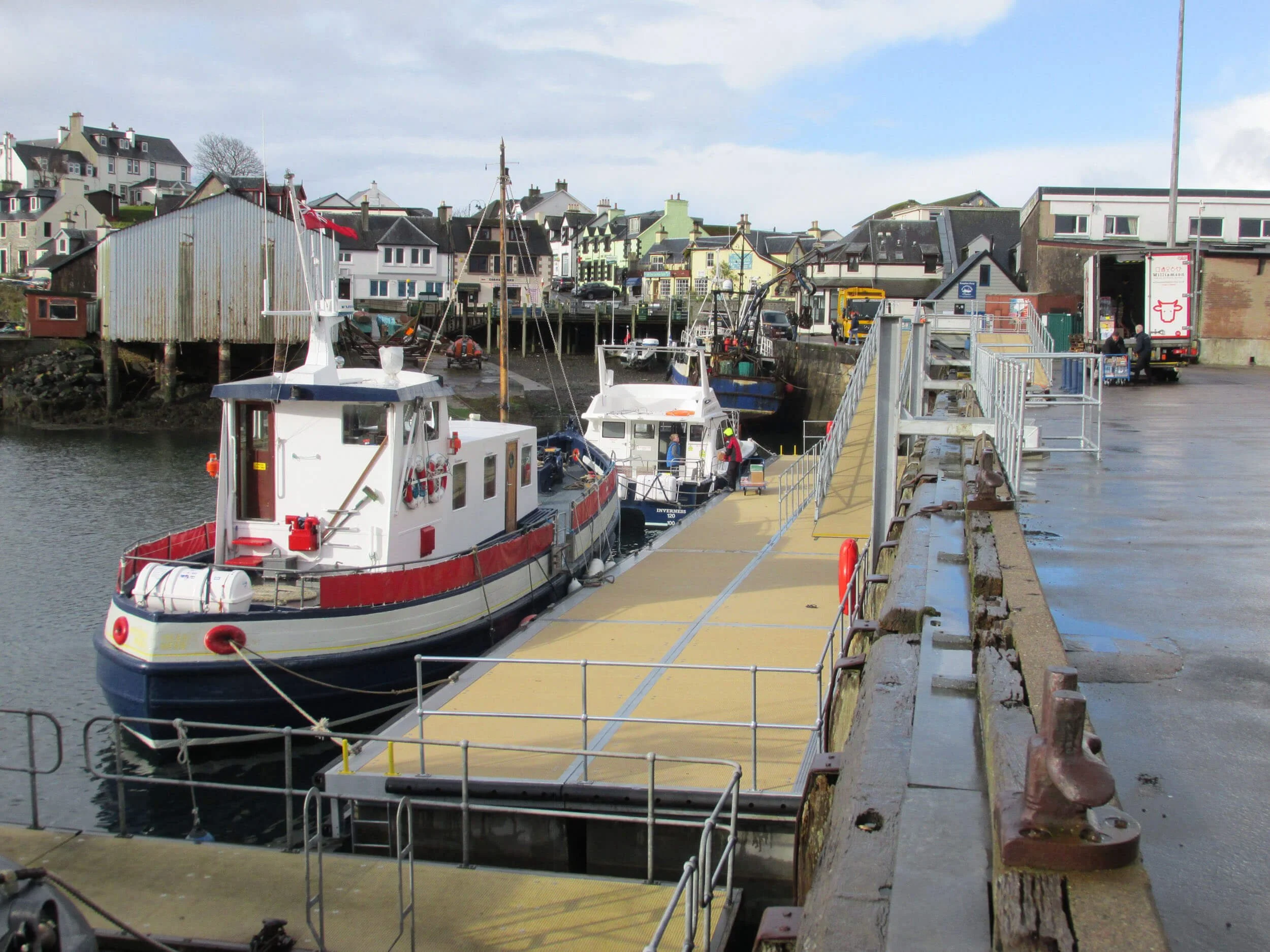 Group of six people wearing yellow safety vests standing in front of boats at a marina on a sunny day.
