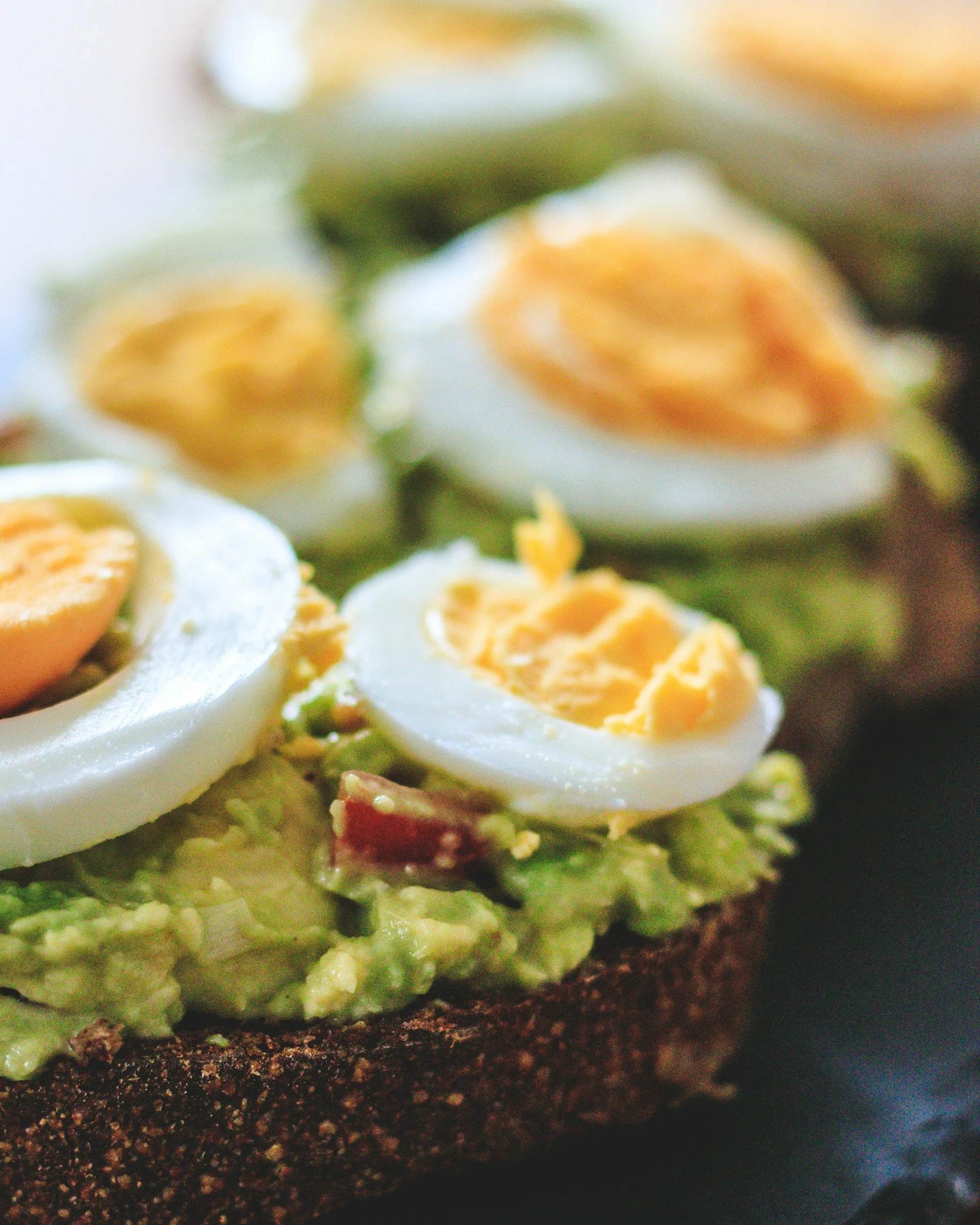 Close-up of an avocado toast topped with sliced hard-boiled eggs.