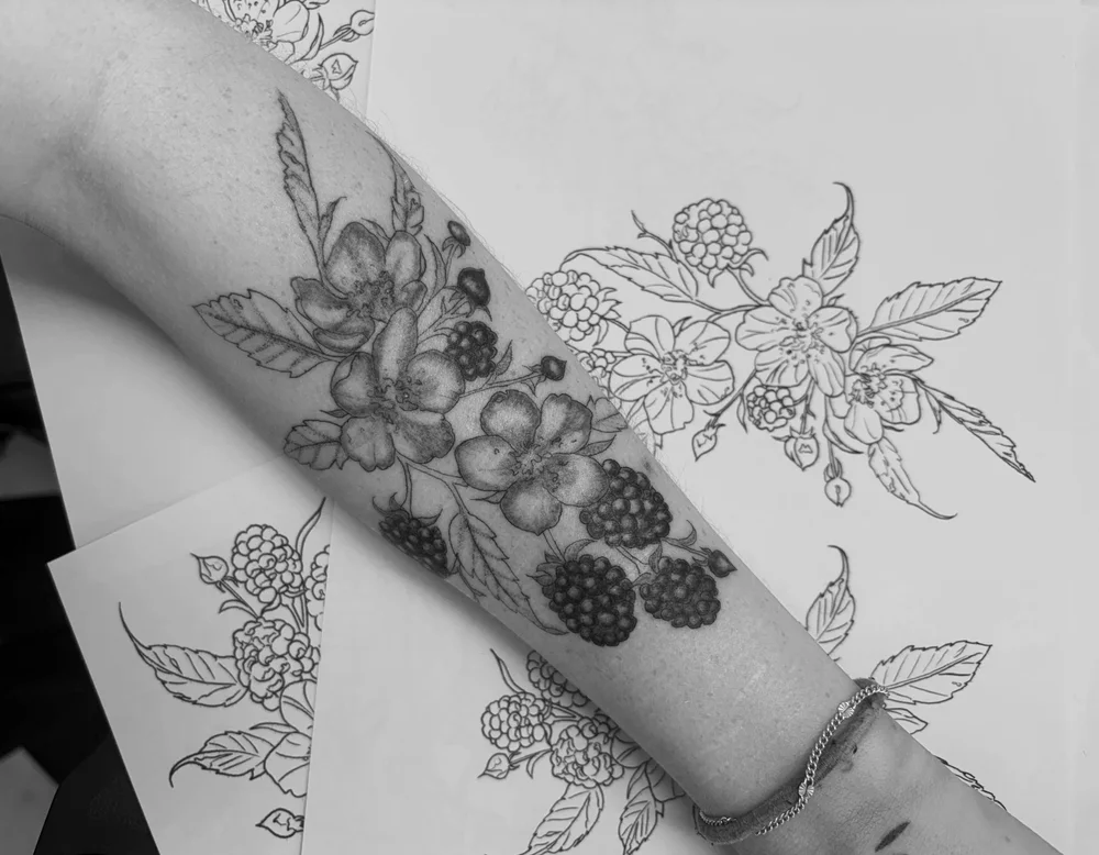 Fine line forearm tattoo photographed in dim indoor light