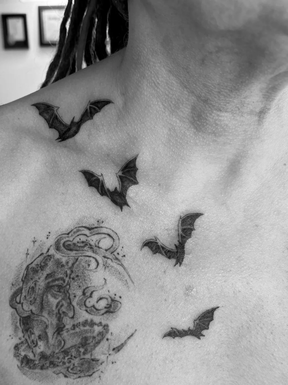 Three fine line bats tattooed across a collarbone