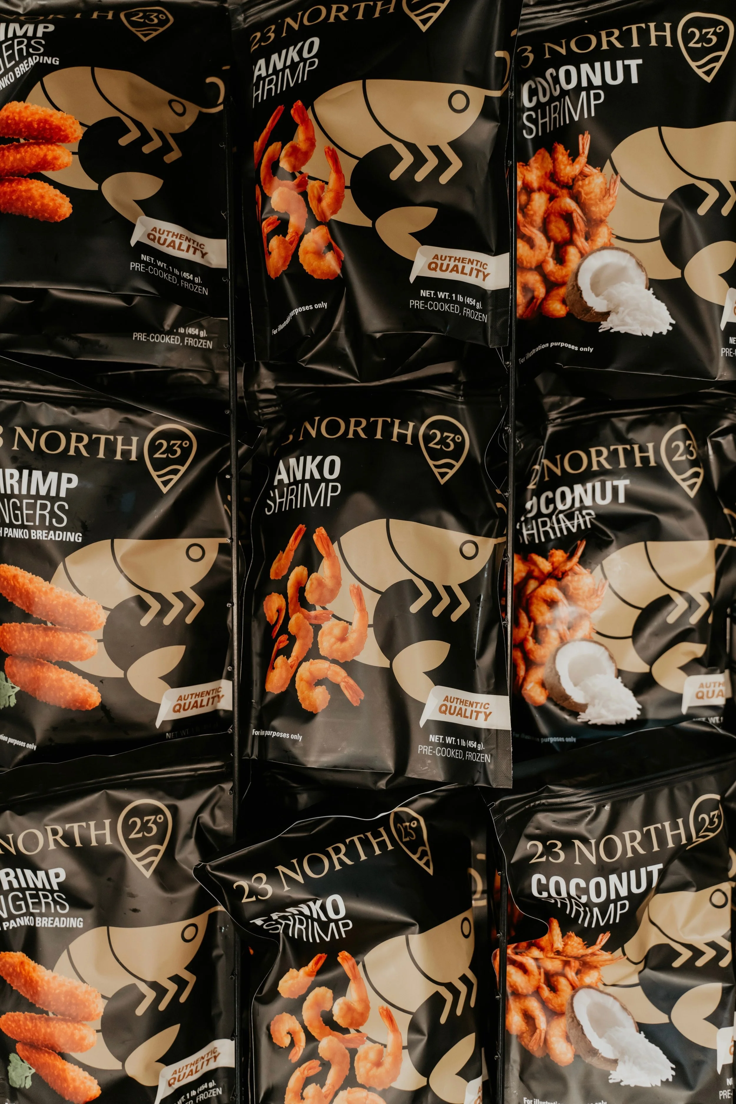 Display of multiple black bags of frozen seafood seafood, including coconut shrimp and shrimp tender pieces, arranged on a store shelf.