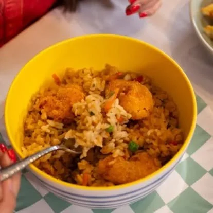 Bowl of fried rice with vegetables and fried chicken pieces
