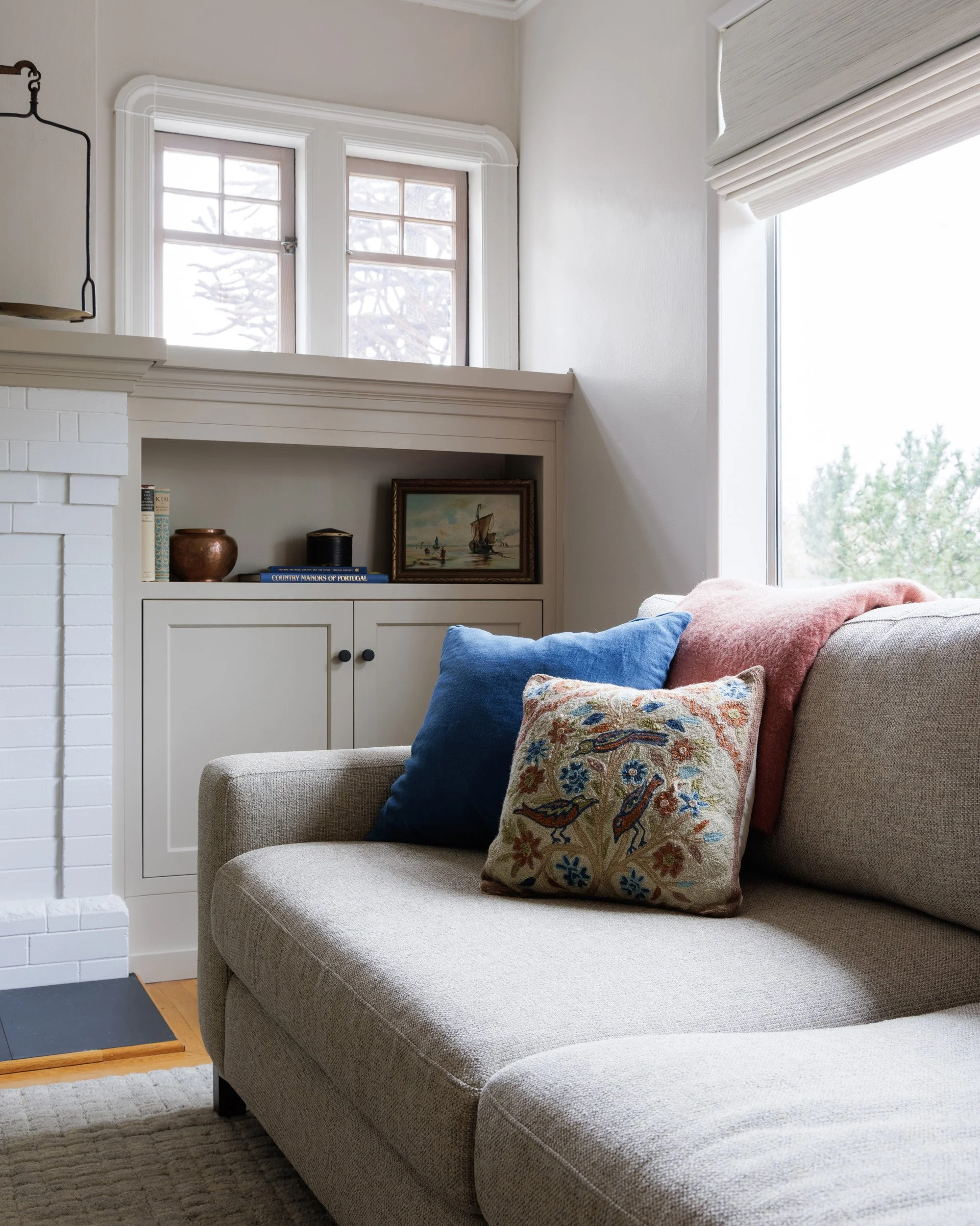 A transitional living room with a beige sofa, colorful pillows, and custom built-in shelves by Full Bloom Interior Design in Seattle.