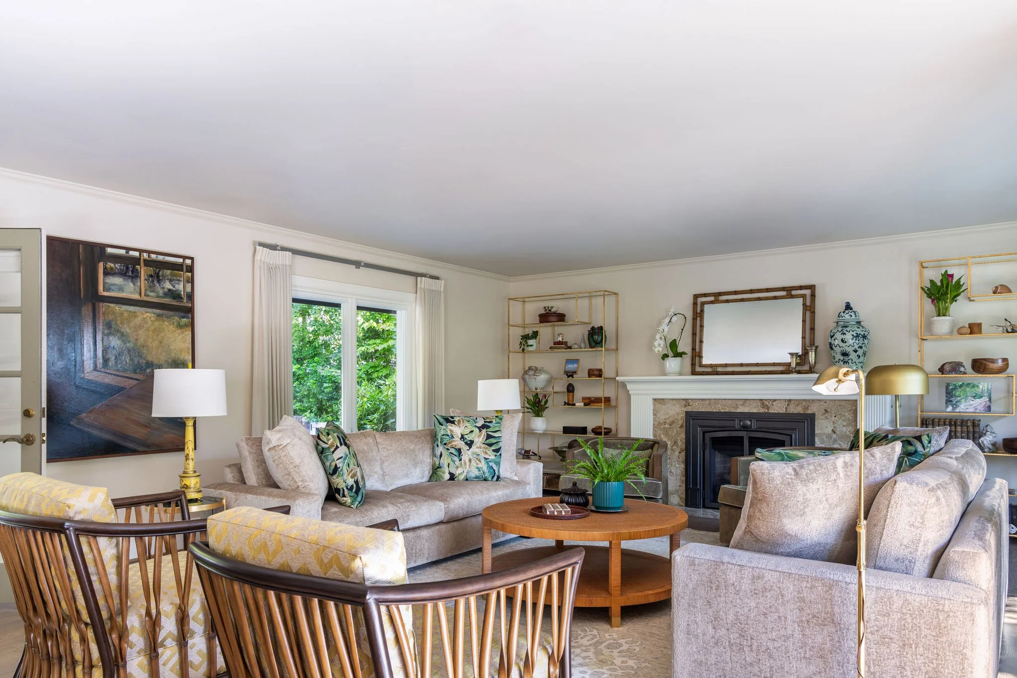 Tropical living room featuring cream sofas, bamboo armchairs, olive green velvet armchairs, a round cane coffee table and decor by Full Bloom Interior Design in Seattle.