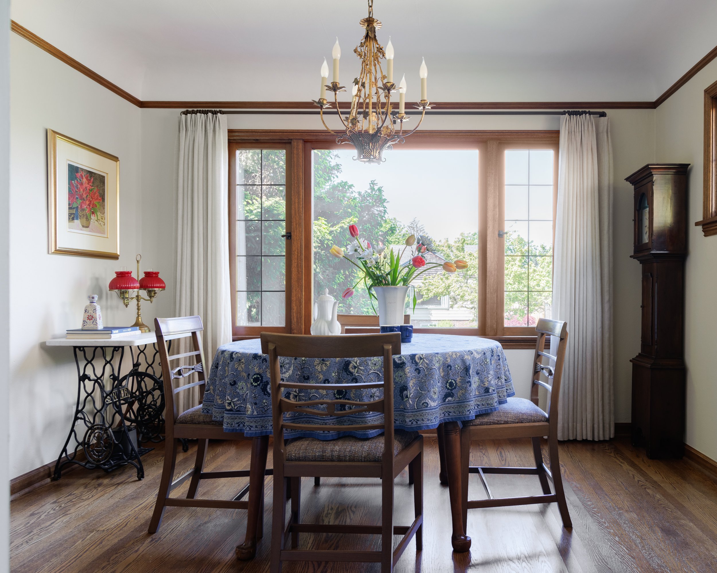 Dining room featuring original wood windows, a vintage chandelier, and a round dining table by Full Bloom Interior Design in Seattle.
