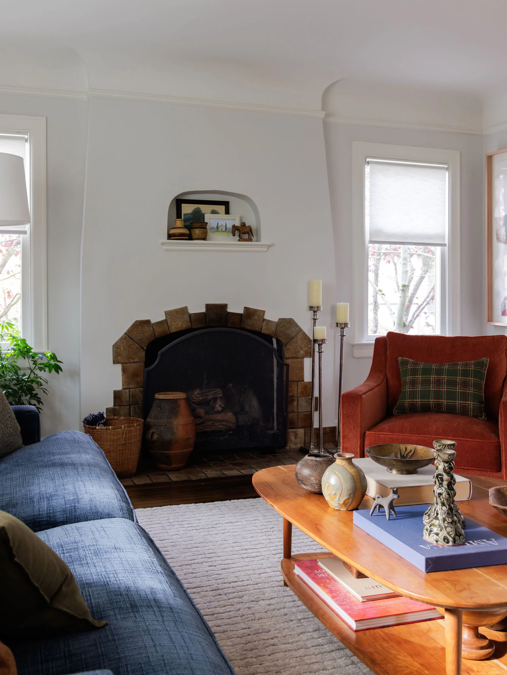 Mid-century wooden coffee table with vintage pottery and a navy blue sofa in a Tudor living room, designed by Full Bloom Interior Design in Seattle.