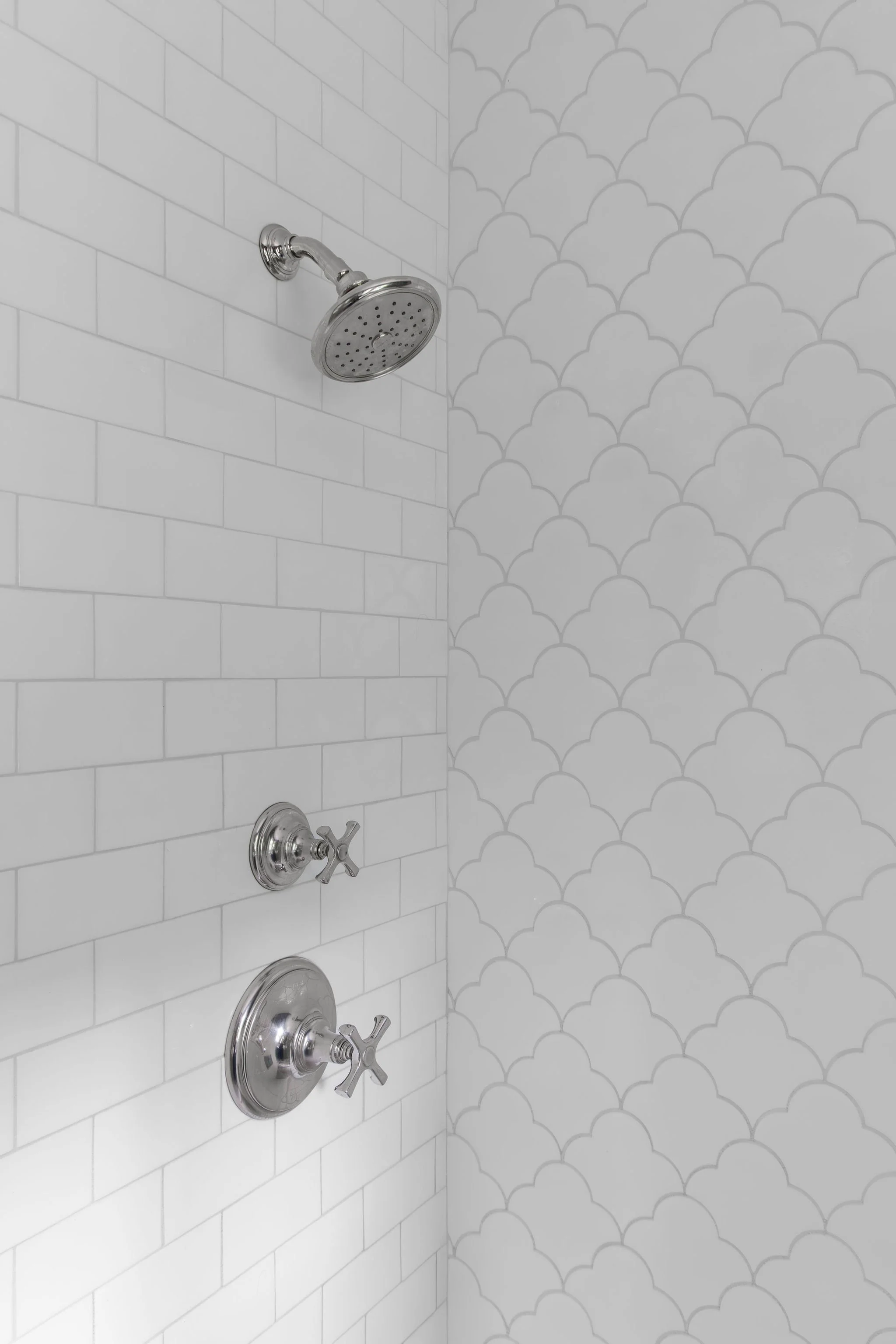 Bright walk-in shower featuring polished nickel fixtures and classic white subway tile paired with a scalloped tile accent wall by Full Bloom Interior Design in Seattle.