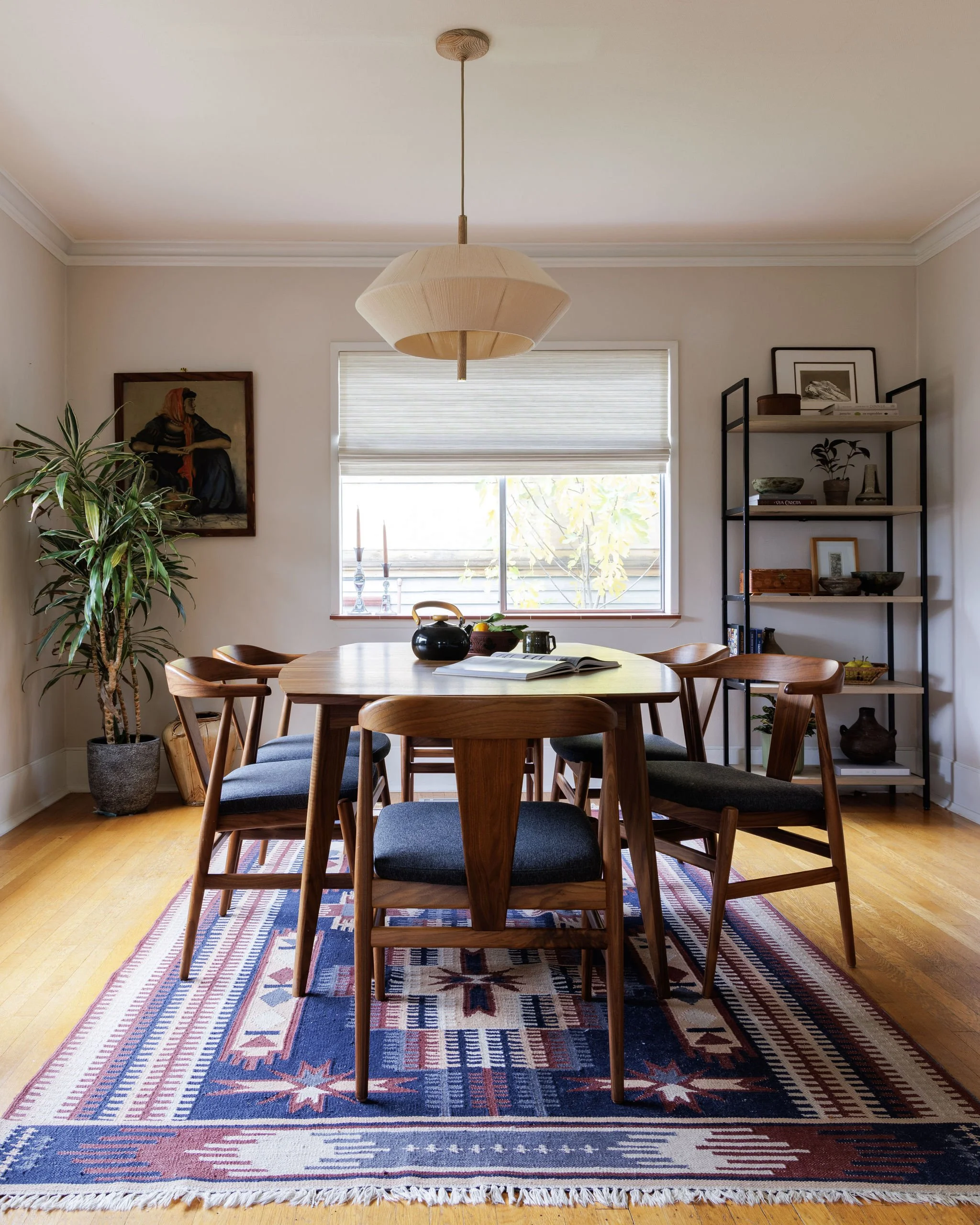 Mid-century modern dining room featuring a walnut table and chairs over a colorful Southwestern rug by Full Bloom Interior Design in Seattle.