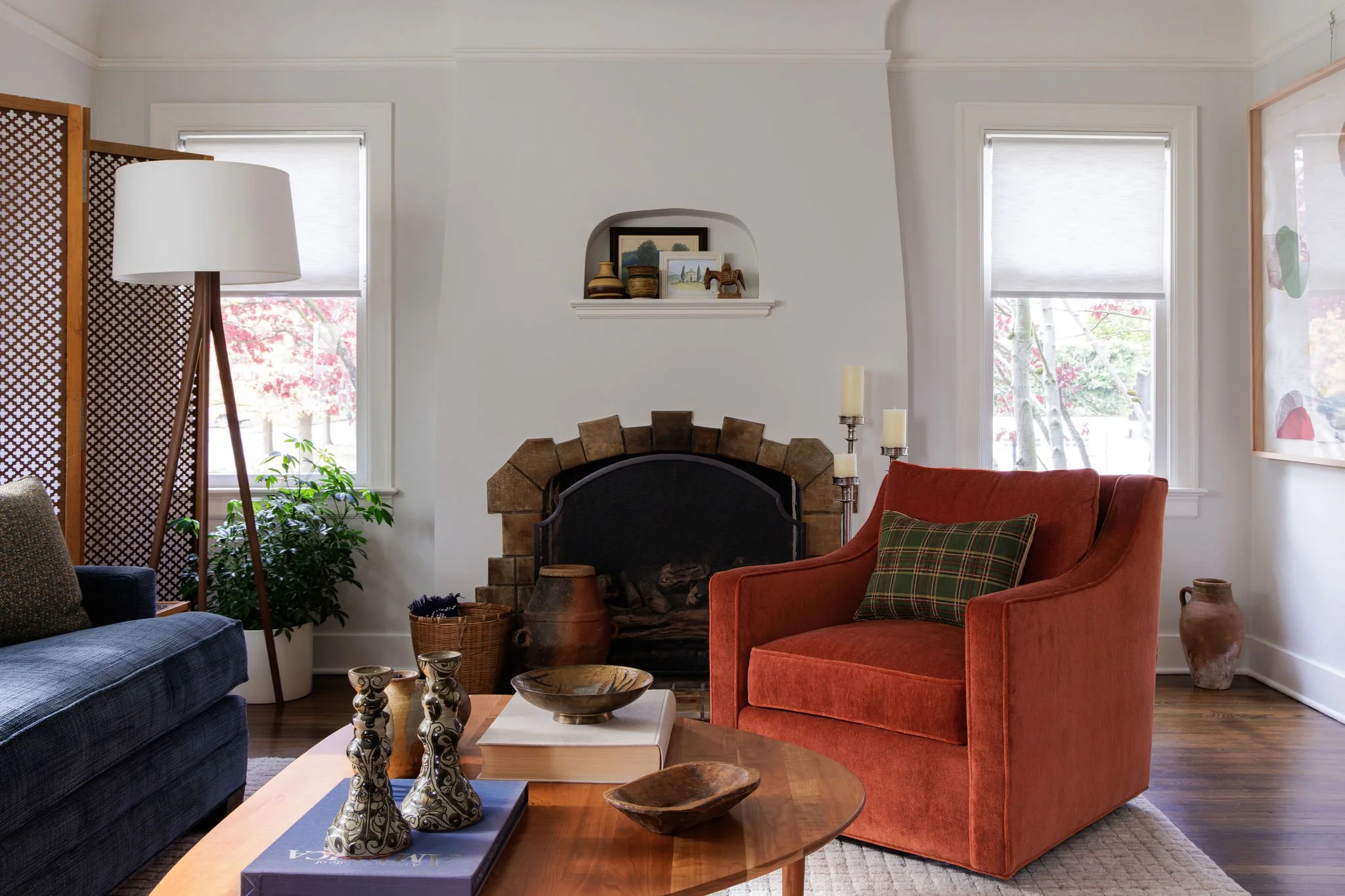 Tudor living room featuring a dark orange velvet chair and a stucco fireplace designed by Full Bloom Interior Design in Seattle.