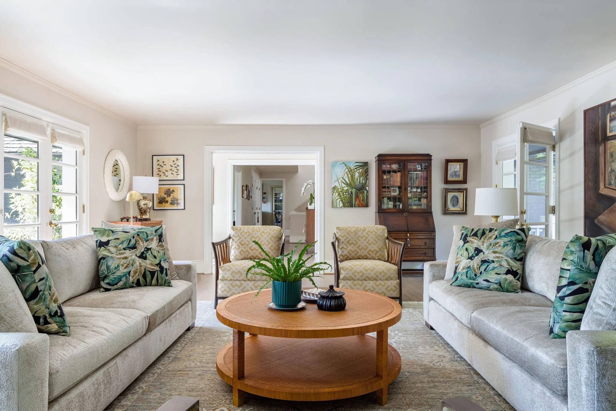 Tropical living room featuring cream sofas, bamboo armchairs, a round cane coffee table and decor by Full Bloom Interior Design in Seattle.