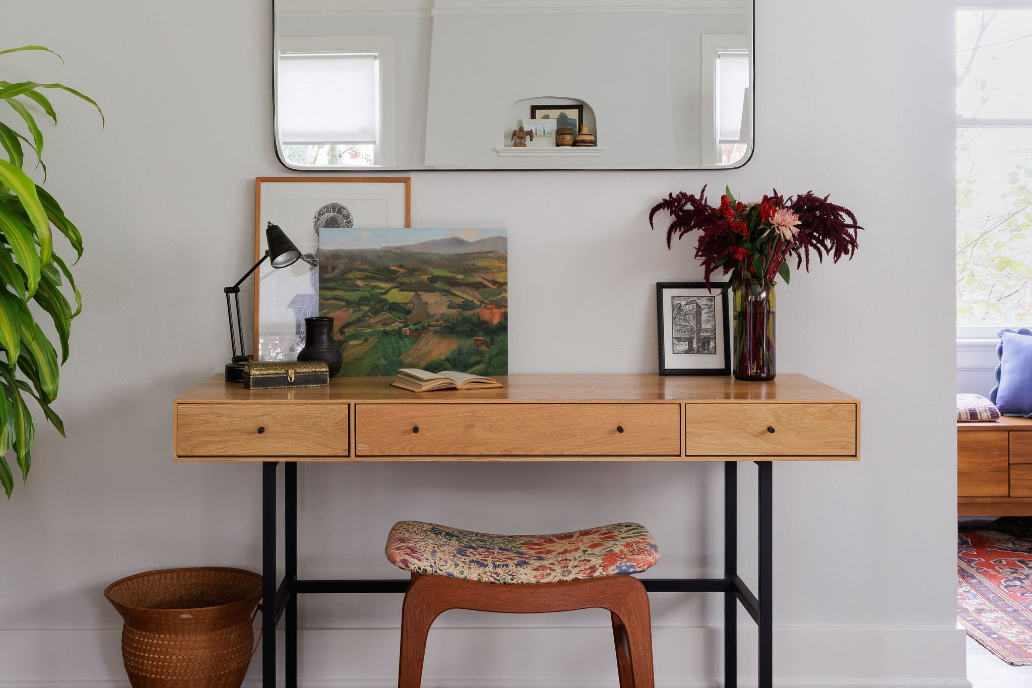 Light wood mid-century desk, floral-patterned stool, and curated tabletop art and decor by Full Bloom Interior Design in Seattle.