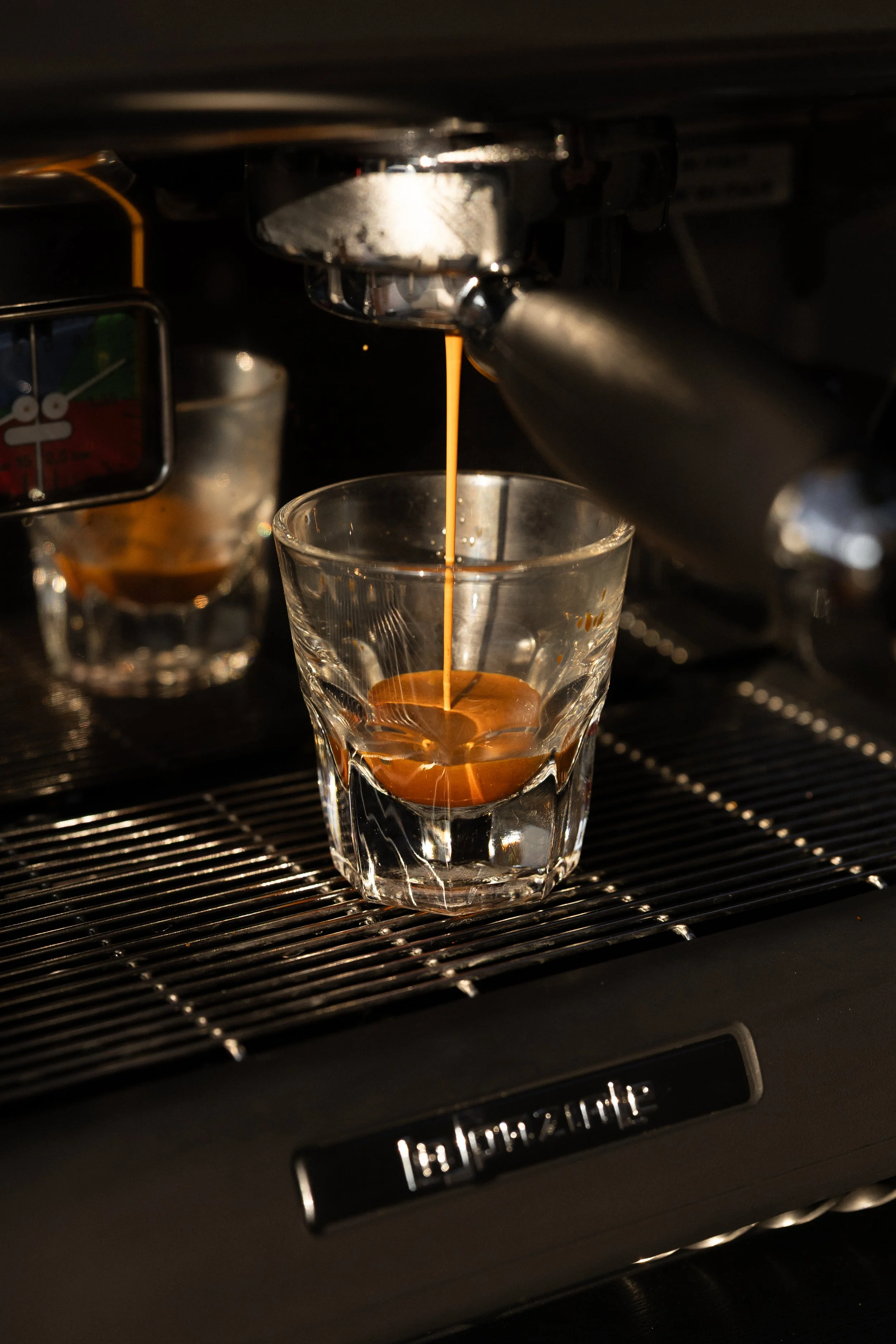 Espresso coffee pouring from an espresso machine into a glass cup.