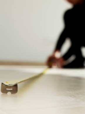 Person measuring a surface with a tape measure.