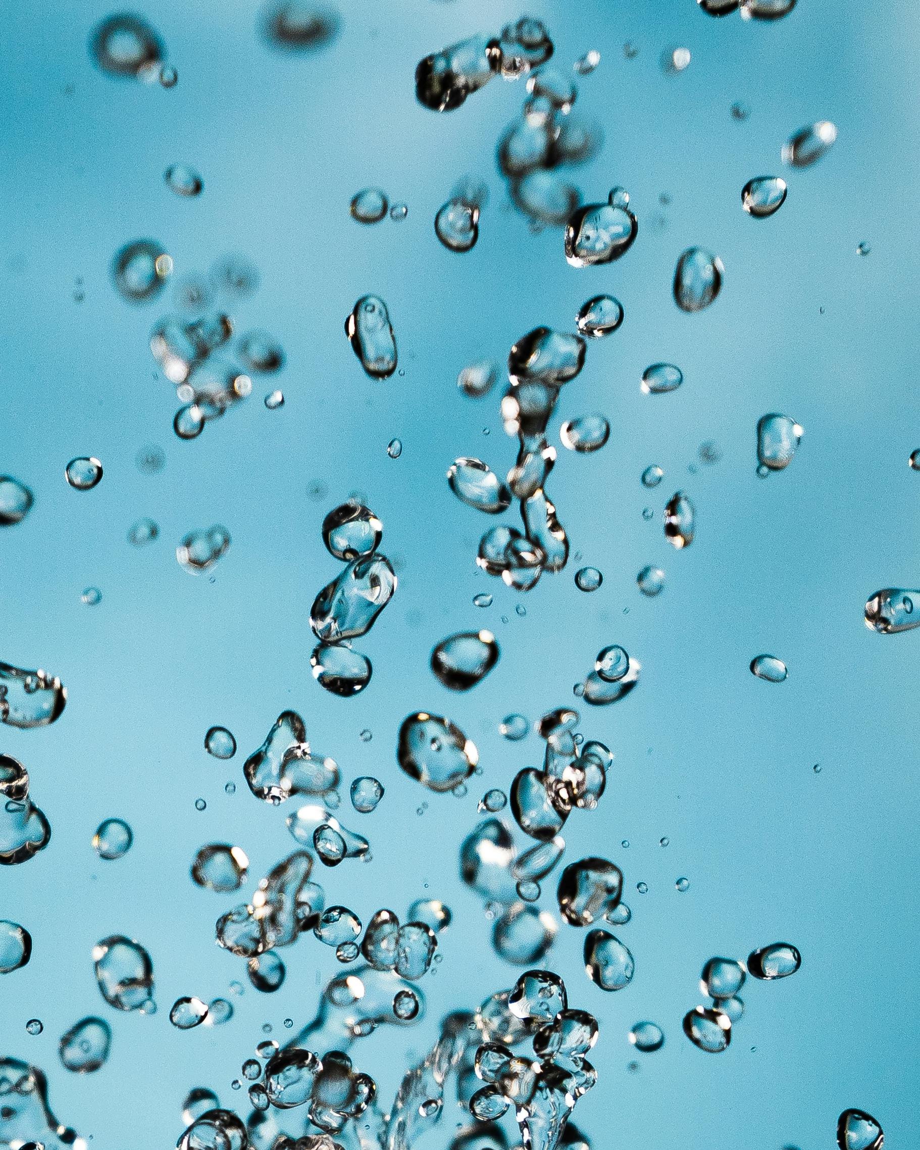 Close-up of water bubbles rising against a blue background.