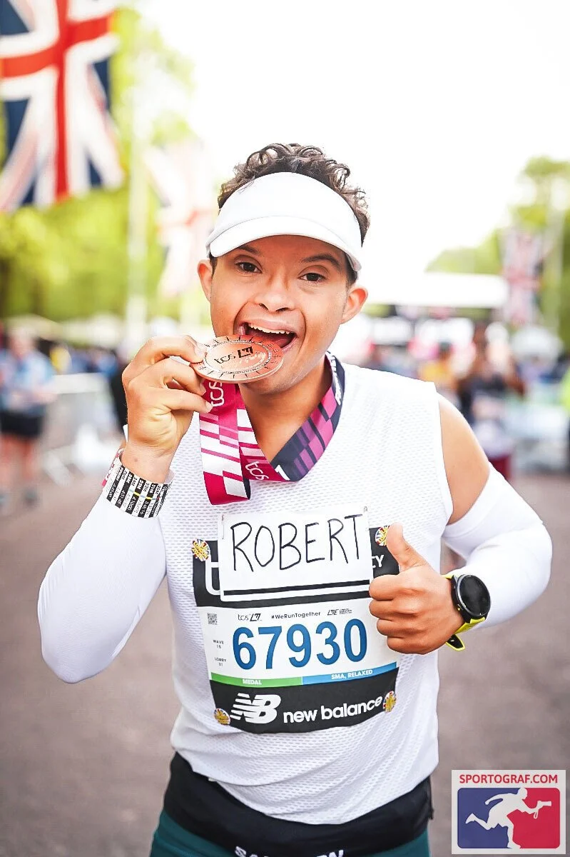 Robert Norris, Man of Iron, crossing the finish line of the London Marathon without a guide and wearing his finisher medal.