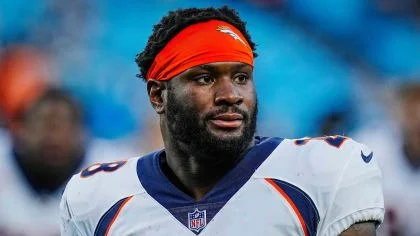 Football player wearing a red headband and white jersey on the field.