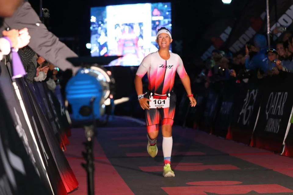 Female athlete smiling as she finishes a race, crossing the finish line.