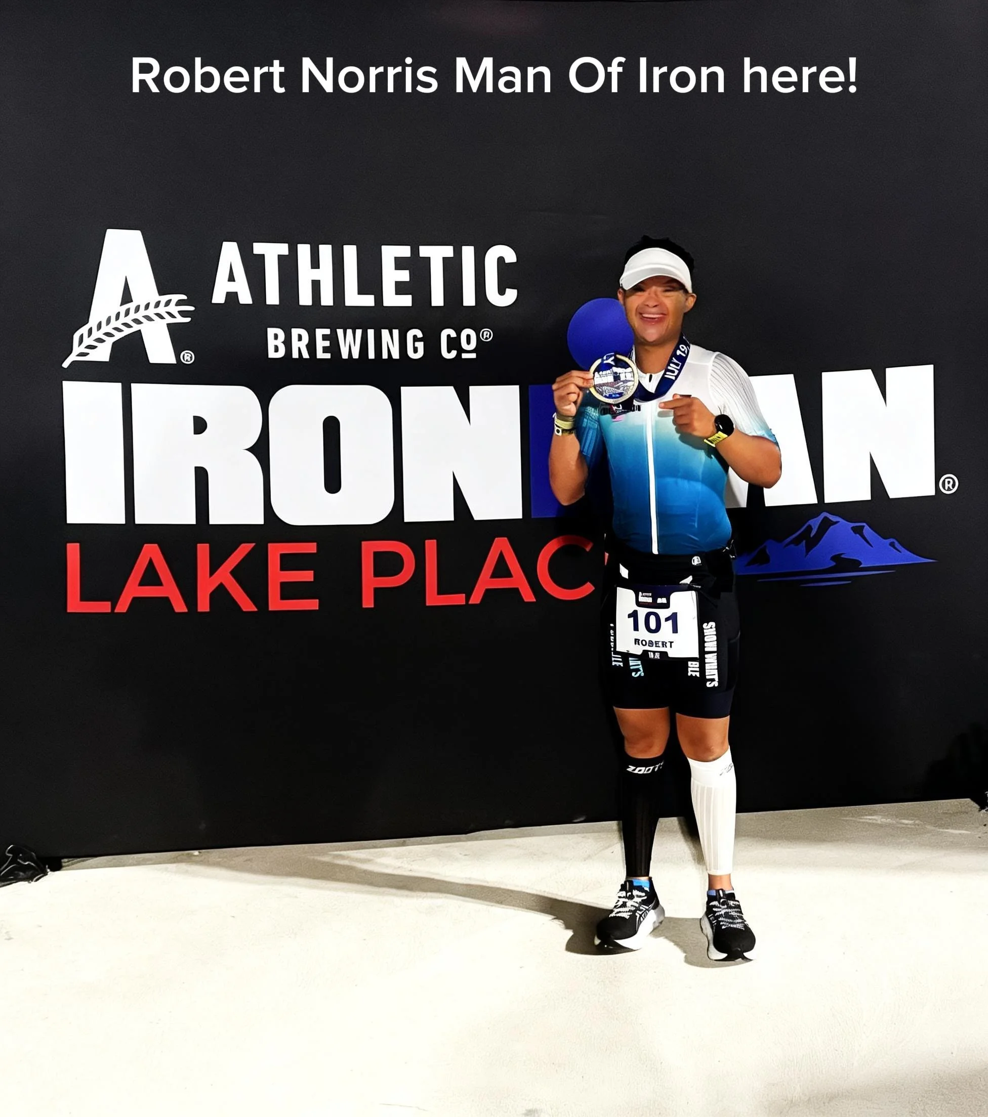 Robert Norris, Man of Iron, celebrating after completing IRONMAN Lake Placid without a guide while holding his finisher medal.