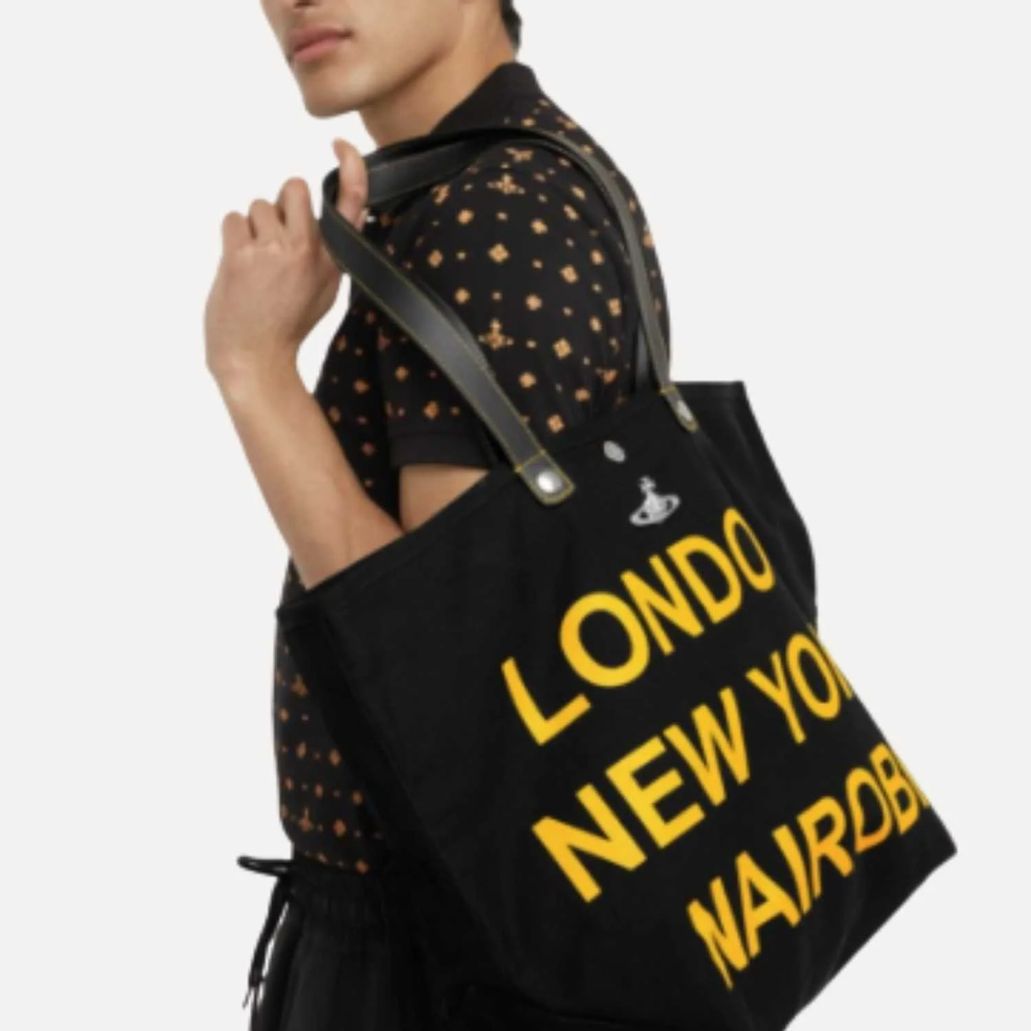 Person carrying an upcycled black shopping bag with yellow text reading "LONDON NEW YORK NARDO" manufactured by Beyond Remade for global fashion brand Vivienne Westwood.